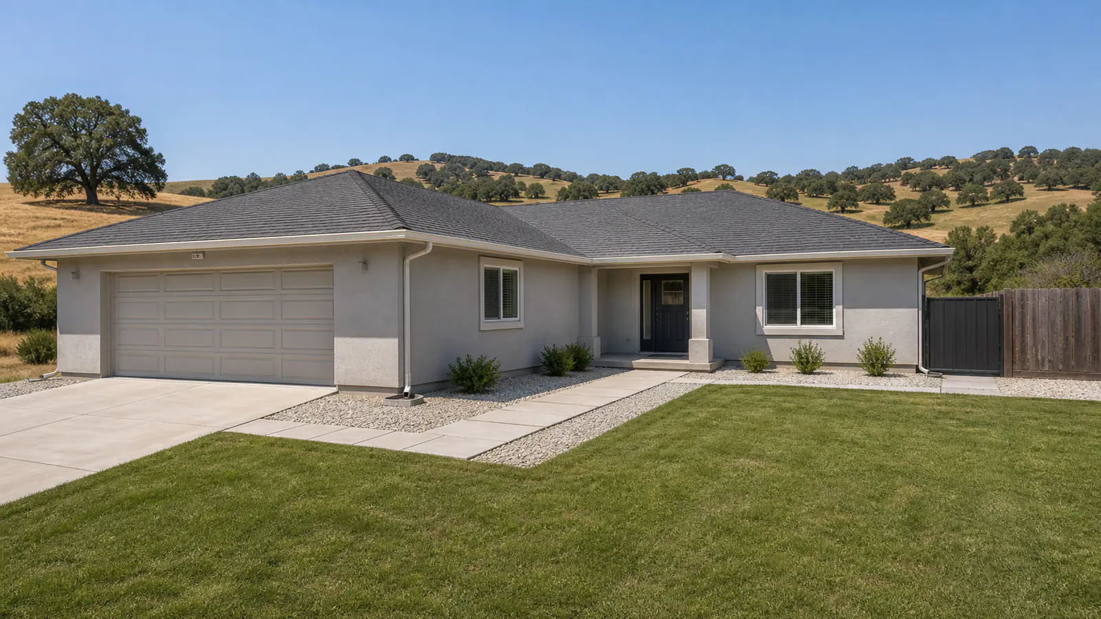 A California hillside home with a five-foot band of gravel and pavers against the foundation, a Class A roof, enclosed eaves, and a metal fence section where the fence meets the house.